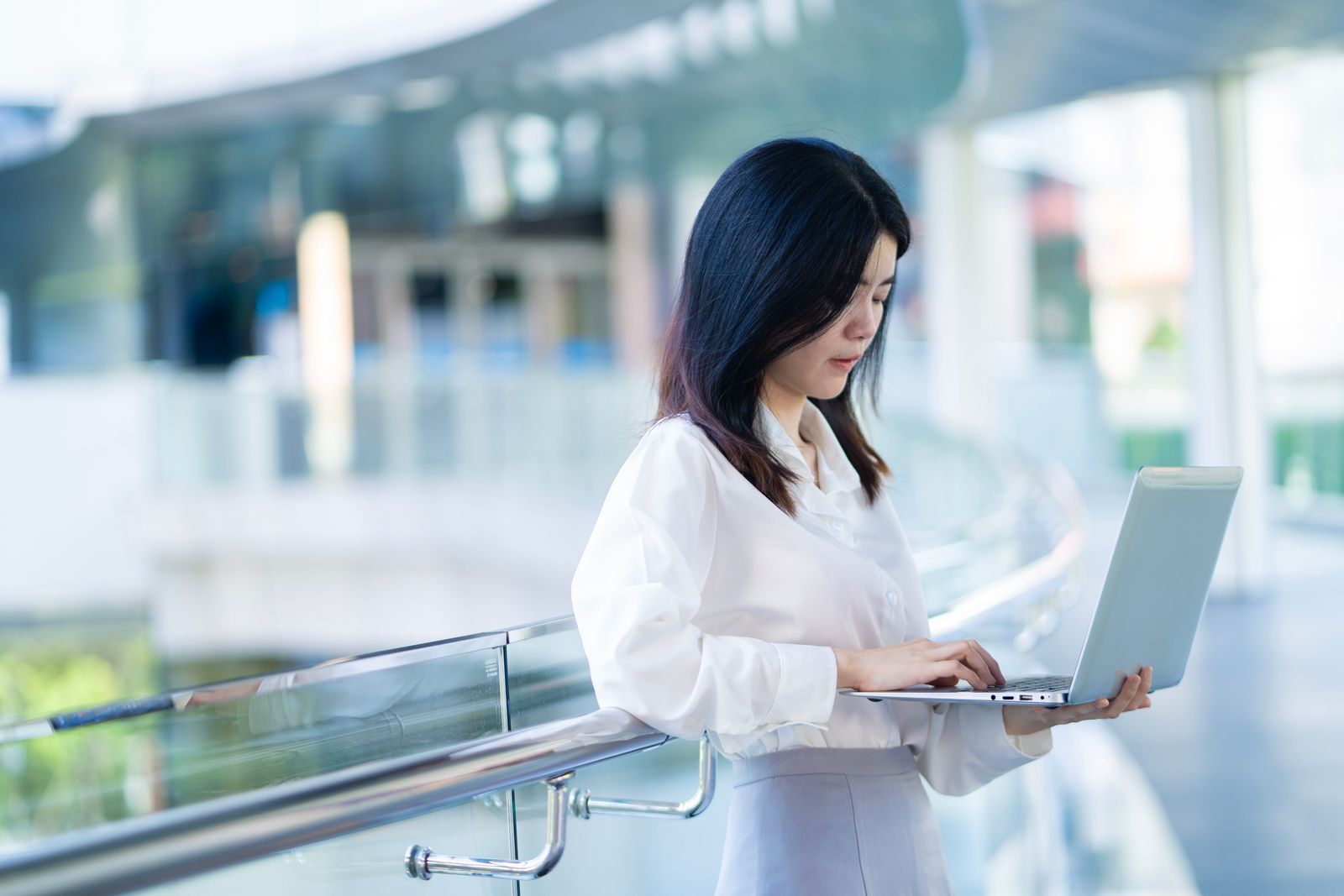 Asian SME professional using a laptop in a modern workspace