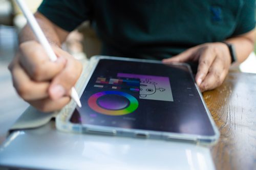 Free Artist using tablet for digital design in a cozy café environment. Perfect for illustrating remote creative work. Stock Photo