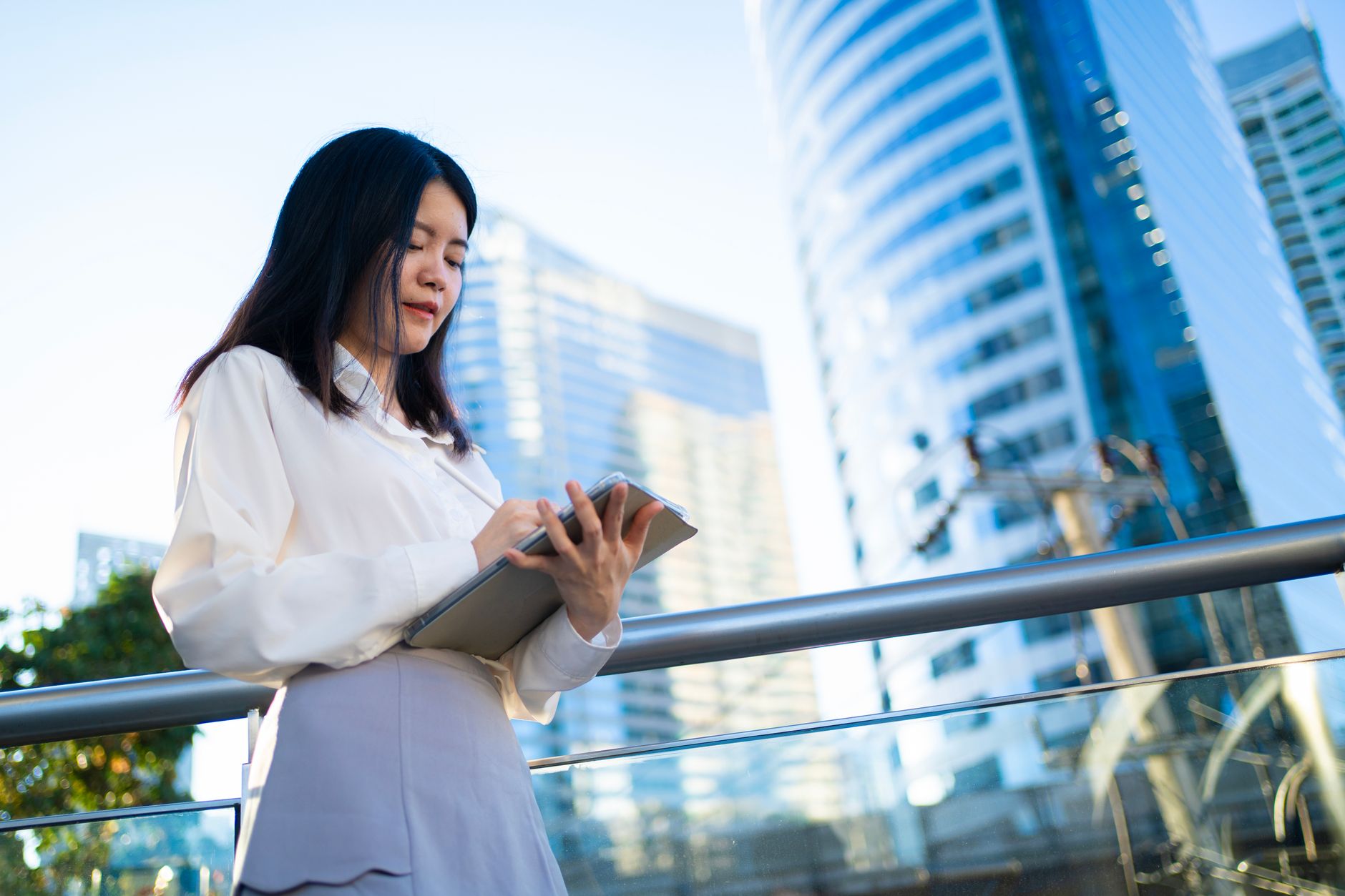 Businesswoman using tablet in modern Bangkok city. Vibrant and professional setting.