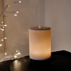 A cylinder diffuser glowing softly on a side table