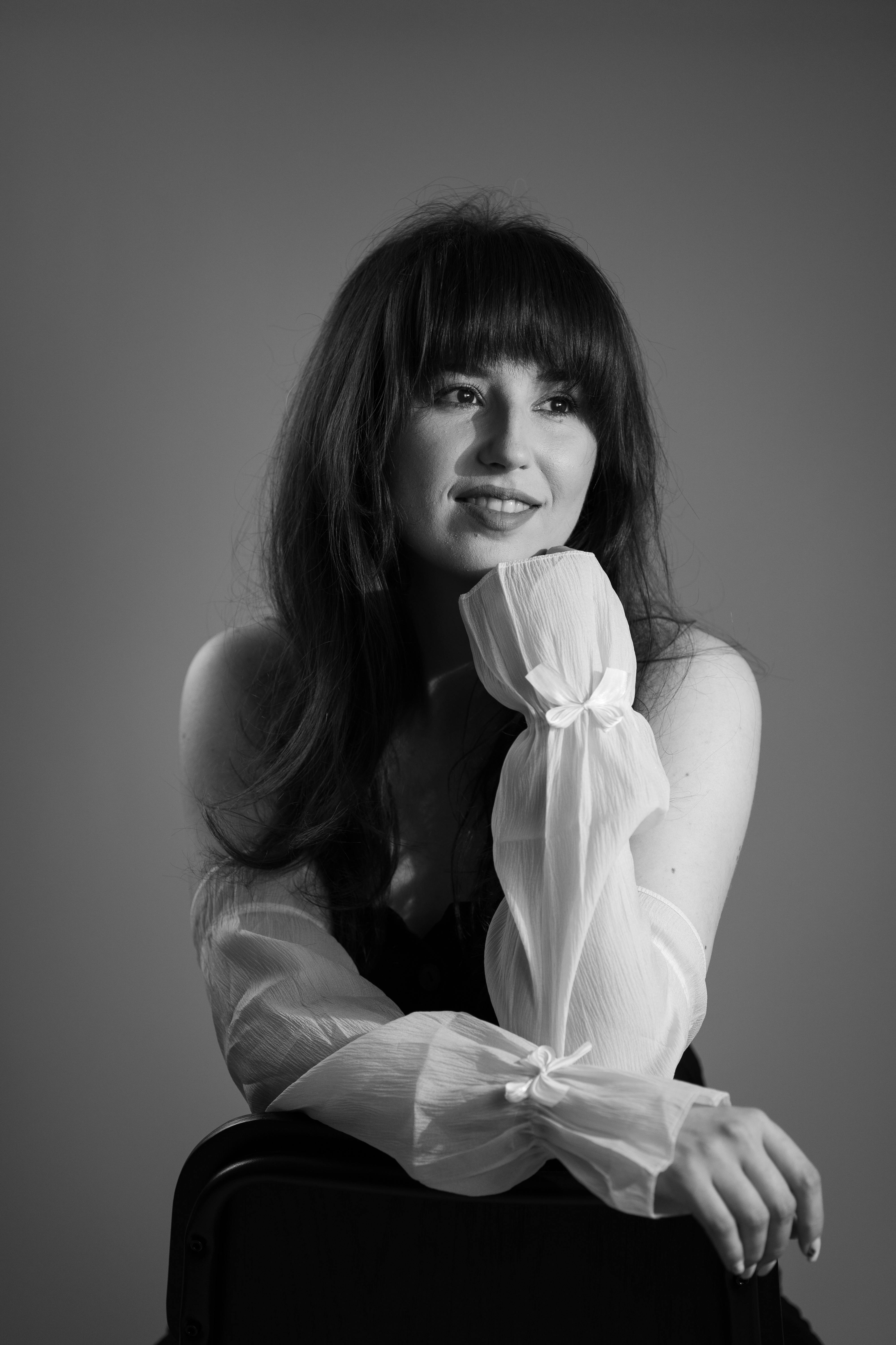 Stylish black and white portrait of a woman in elegant attire and a thoughtful pose.