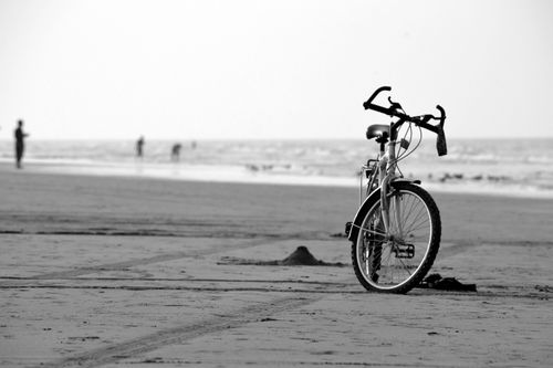 Free A black and white photo of a bicycle parked on Seeb beach, Oman, capturing the essence of solitude and peace. Stock Photo