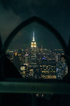 Nighttime view of Manhattan skyline with Empire State Building glowing brightly.
