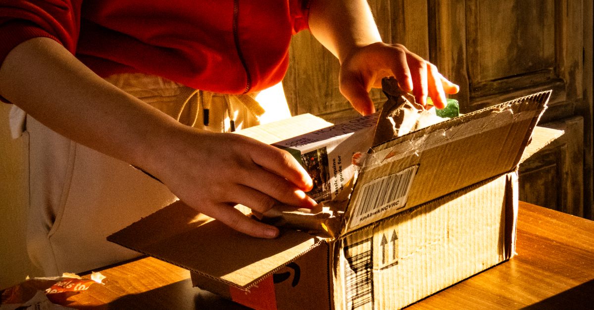 A person unboxing a package, revealing curiosity and anticipation in a warmly lit setting.