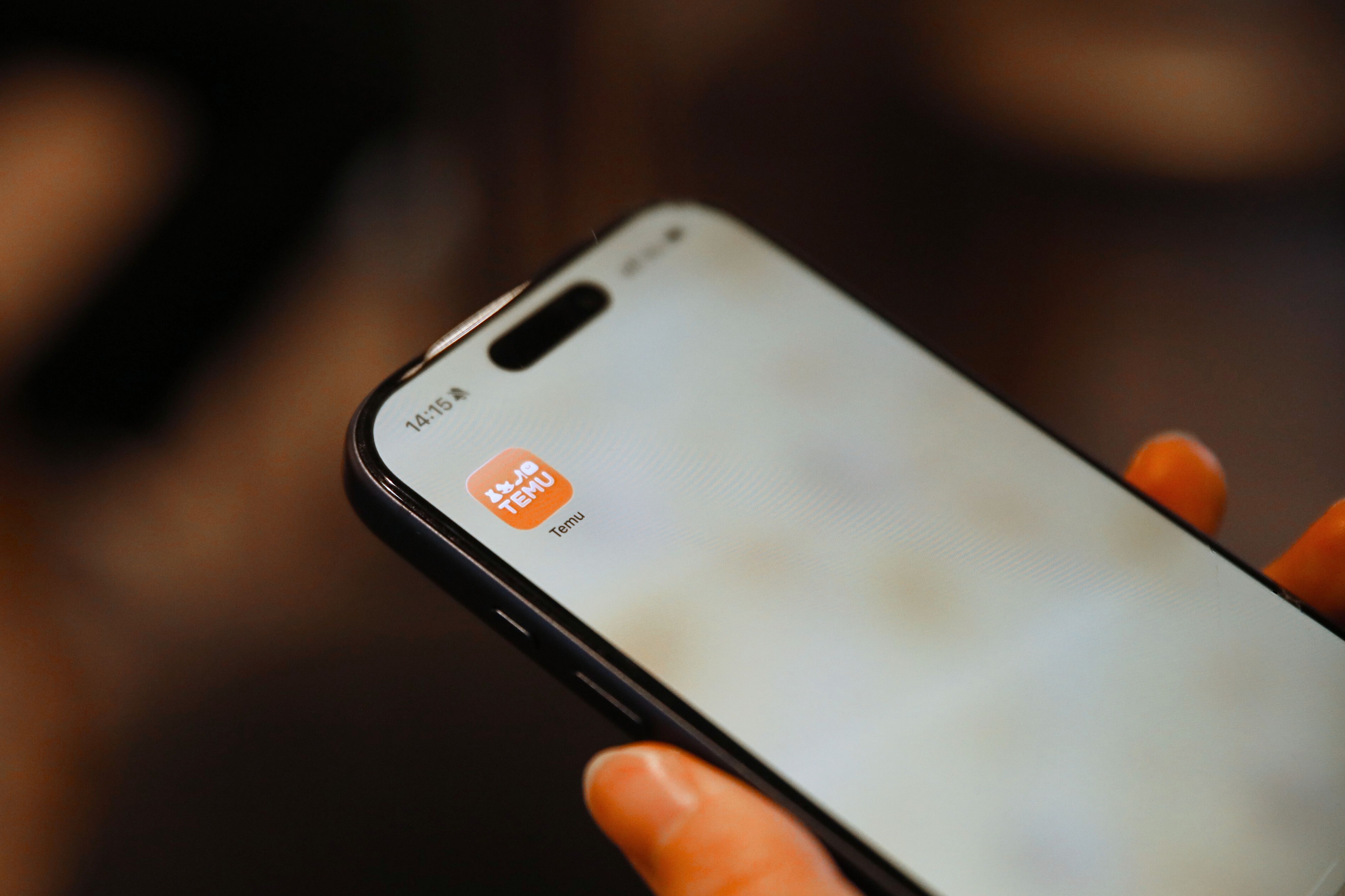 gratis Hand die een smartphone vasthoudt met een zichtbaar pictogram van een winkelapp, gericht op digitaal gemak. Stockfoto