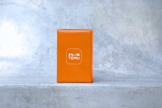 Bright orange parcel with Temu logo on a concrete surface, suitable for ecommerce themes.