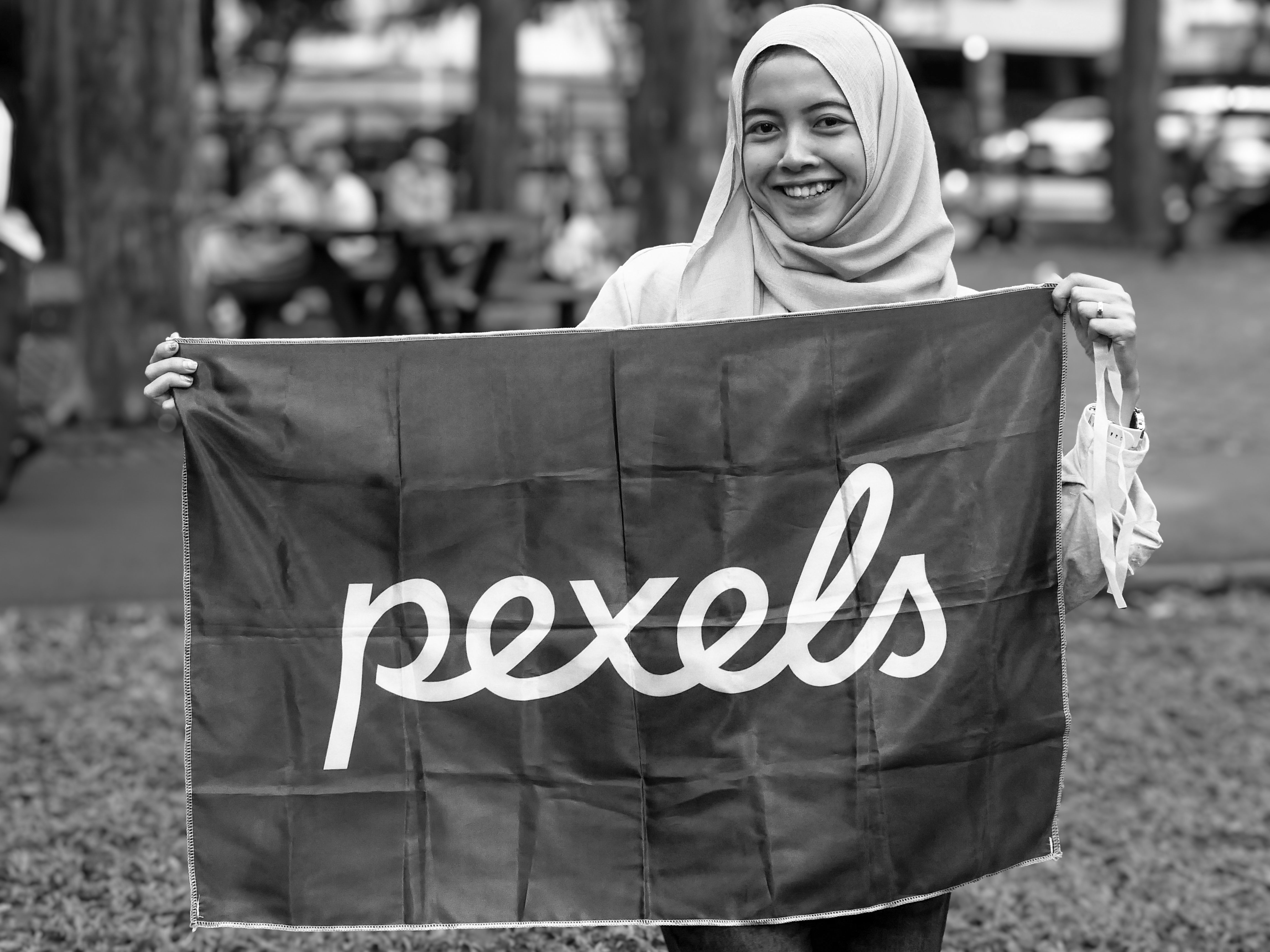 Black and white photo of a woman with a Pexels banner in a park setting.