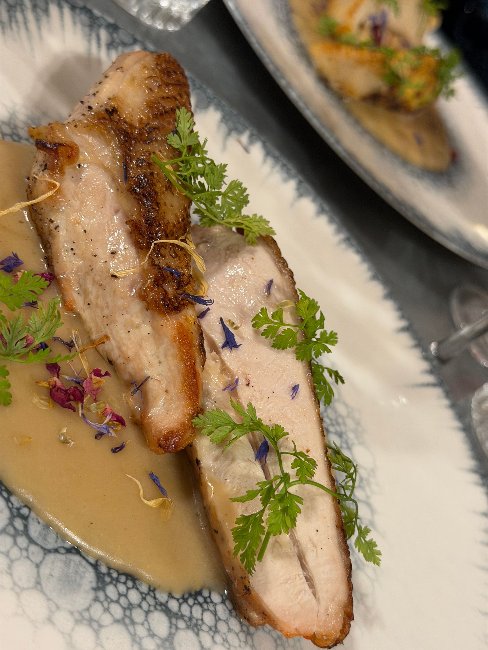 Suprême de volaille rôti tranché, sauce crémeuse, cerfeuil et pétales de bleuet