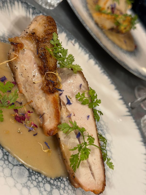 Suprême de volaille rôti tranché, sauce crémeuse, cerfeuil et pétales de bleuet