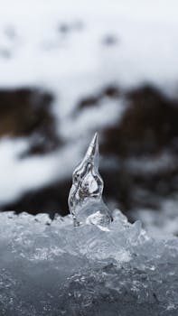 Detailed shot of a unique ice formation resembling a sharp peak amidst snow, showcasing nature's artistry.