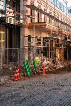 A city street under renovation with scaffolding and construction equipment during the day.