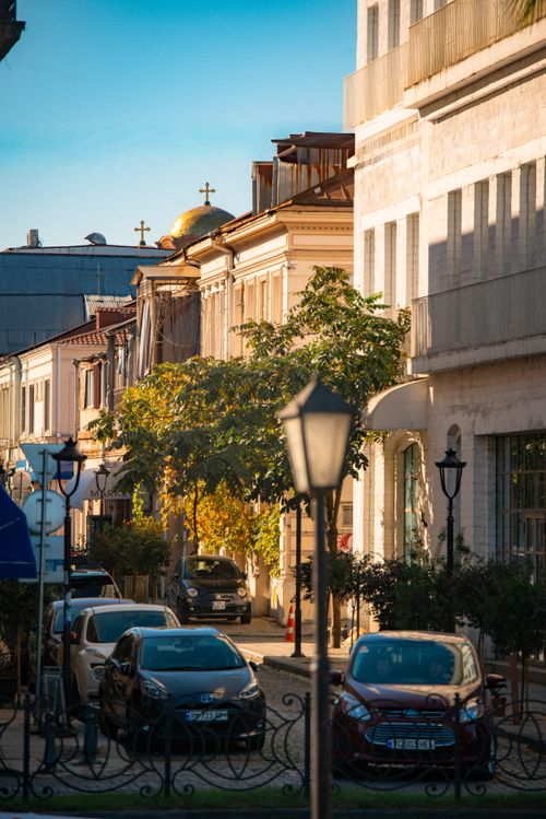 Free Sunny afternoon street scene with historic architecture and parked cars in a European city. Stock Photo