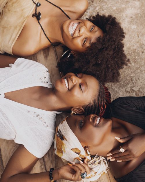Free Three African women sharing a joyful moment lying outdoors, radiating happiness and friendship. Stock Photo