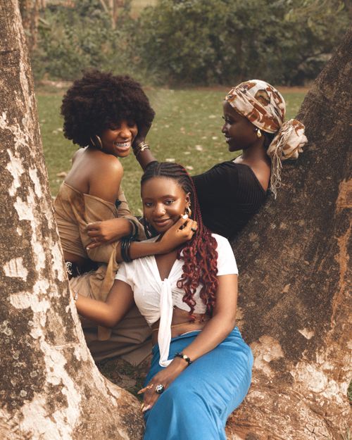 Free Three women smiling and enjoying nature beneath a large tree. Stock Photo