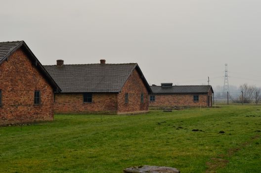 Brick buildings with historical significance on a grassy field under a cloudy sky.