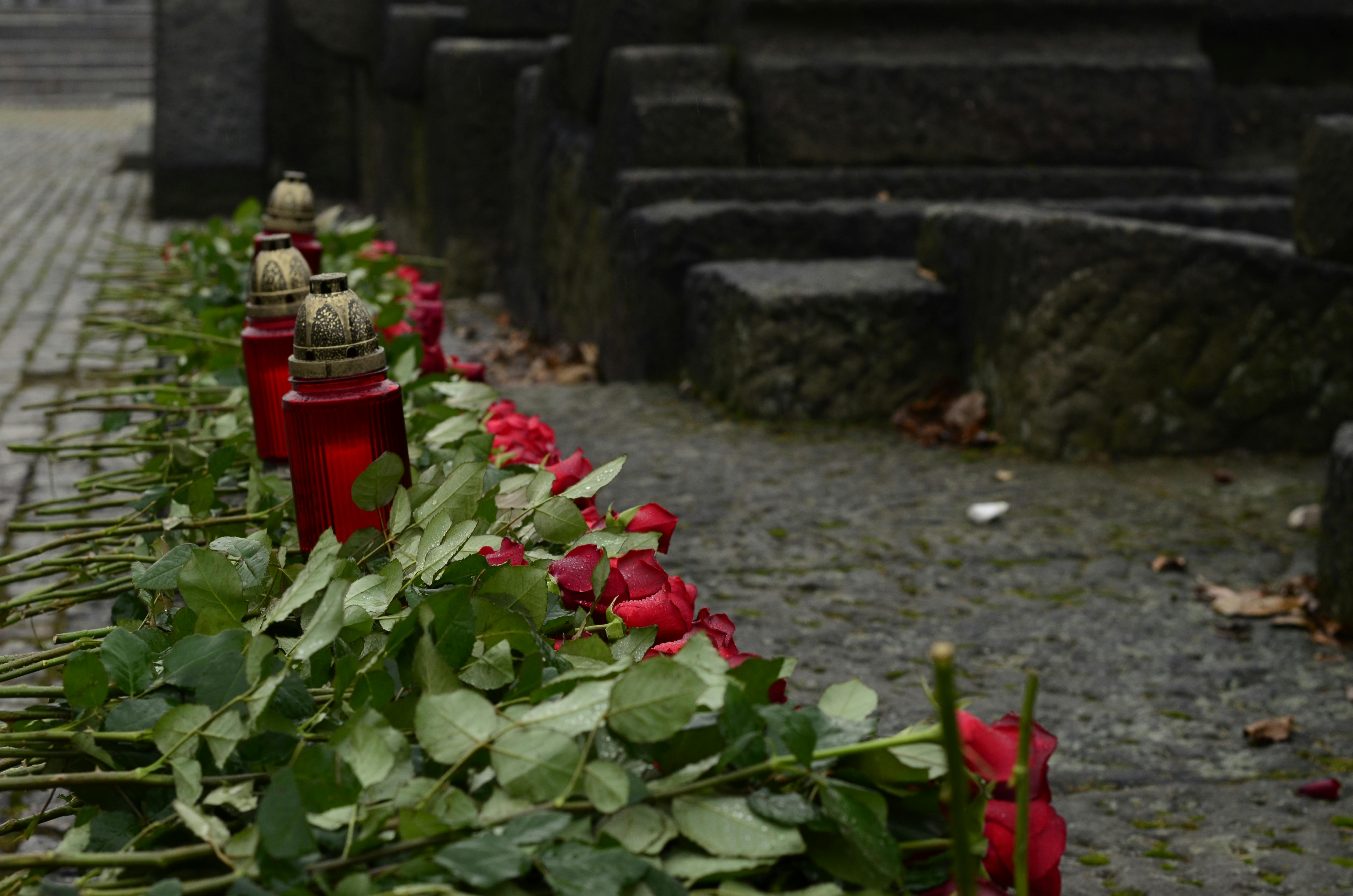 Memorial candles and roses on stone steps, echoing ritual rather than resort polish.