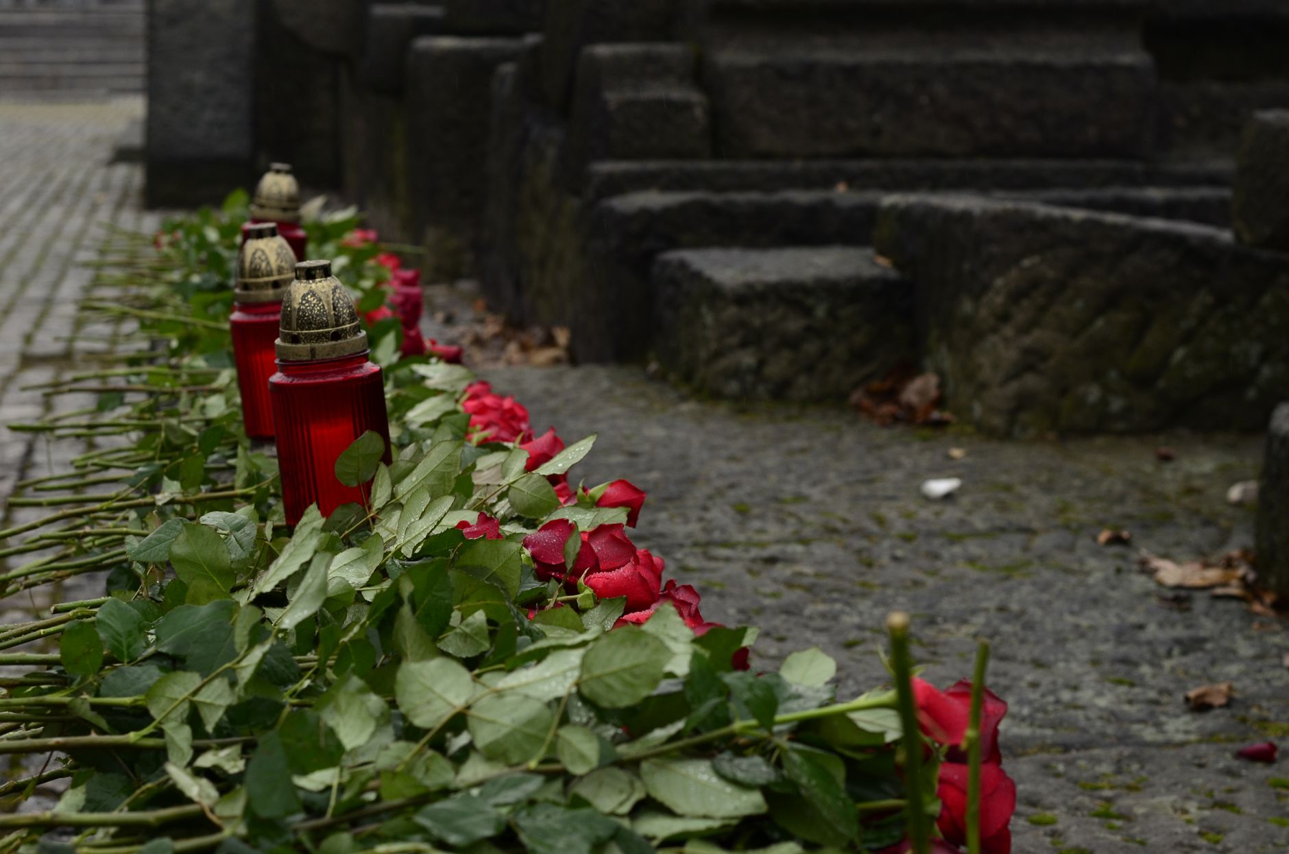 Memorial candles and roses on stone steps, echoing ritual rather than resort polish.