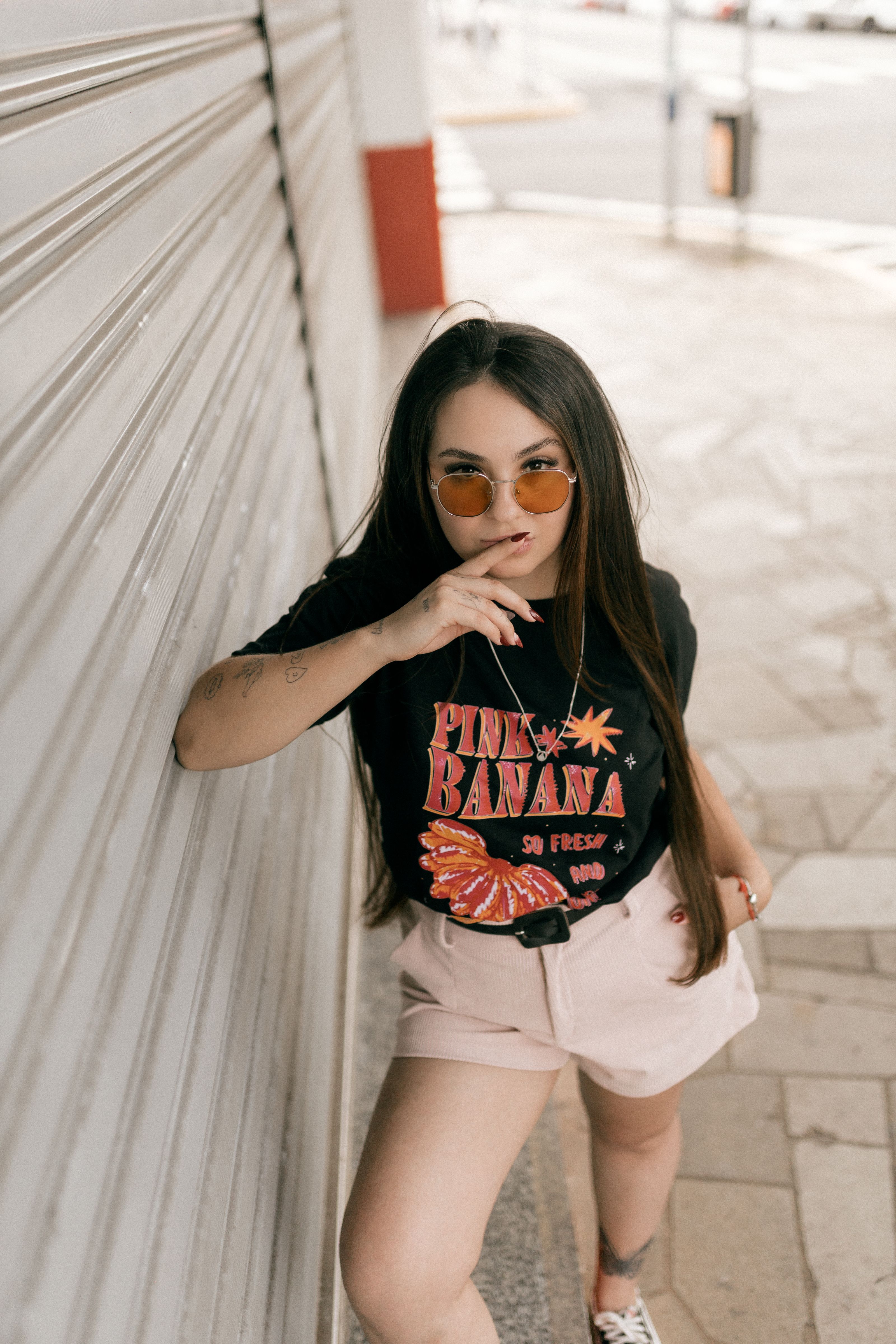 Mulher fashionista de óculos escuros posando confiantemente na rua da cidade.