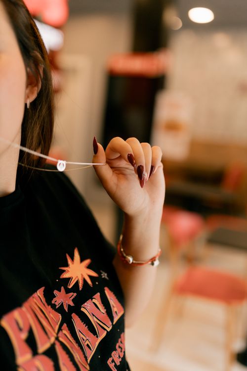 Free Artistic close-up of a woman's hand showcasing elegant nail art while holding a necklace indoors. Stock Photo