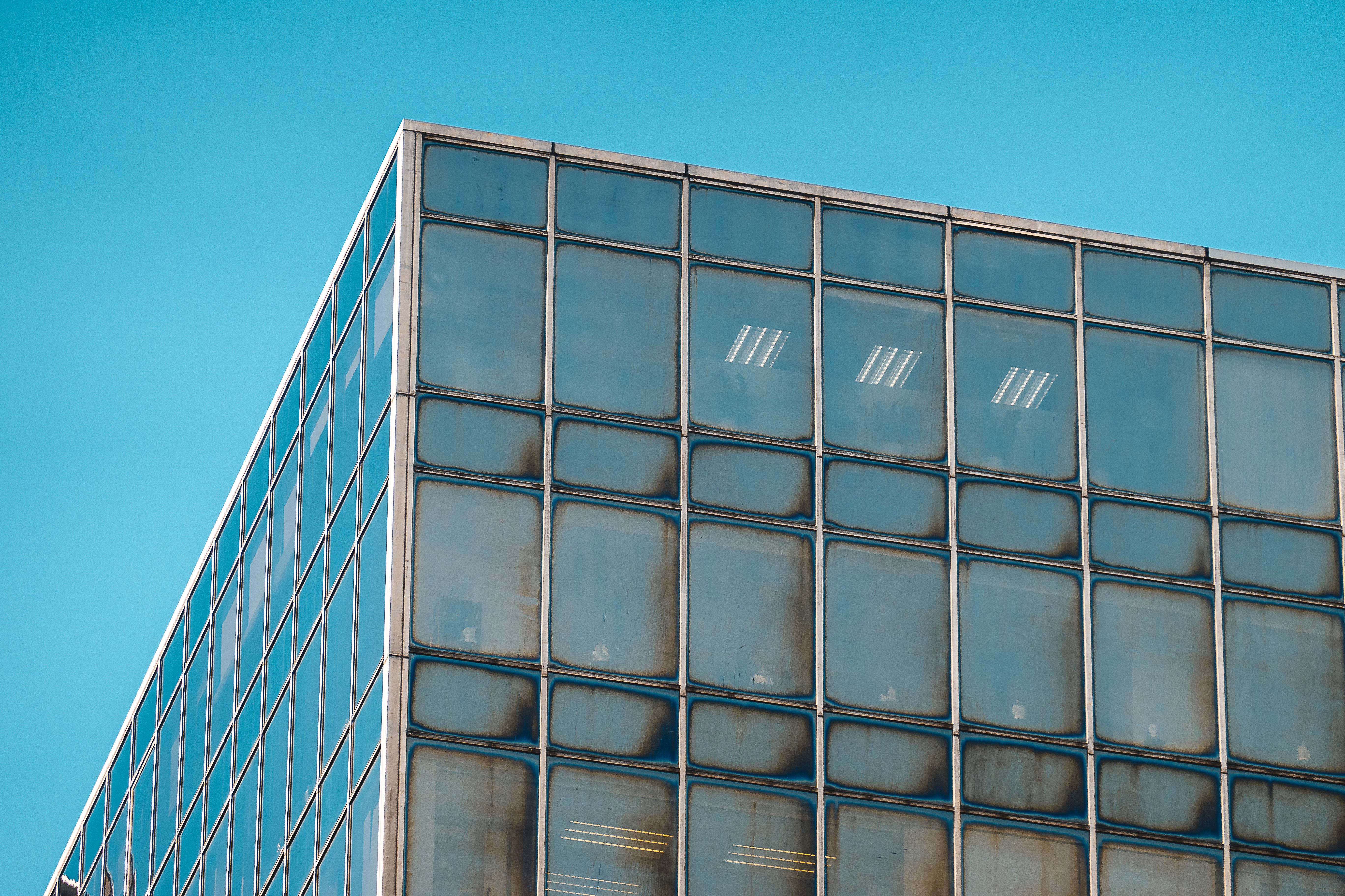 Modern glass building facade against clear blue sky · Free Stock Photo