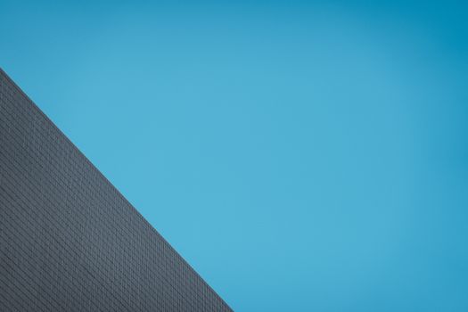 Geometric building facade captures modern architecture in Hong Kong against a clear sky.