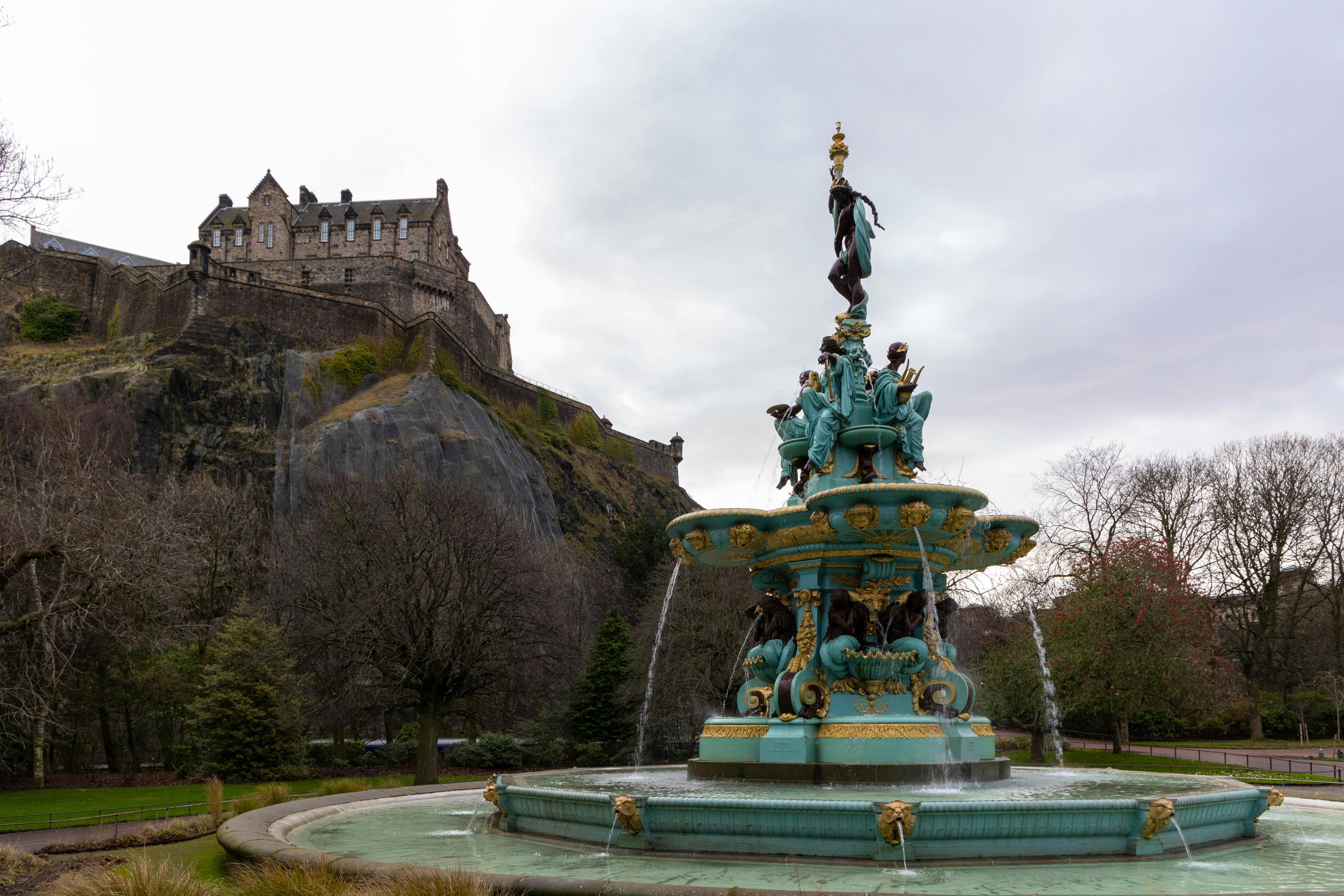 Scenic view of Ross Fountain with Edinburgh Castle in the background on an overcast autumn day.