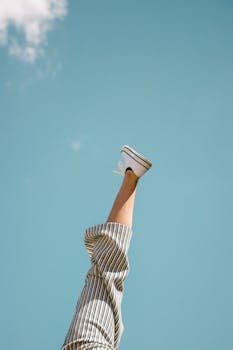 一条腿穿着条纹裤子，在明亮的蓝天下开玩笑地向上伸