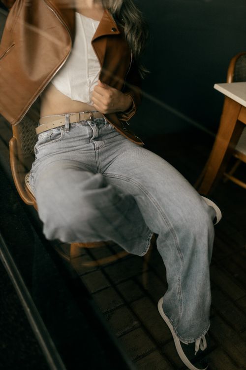 Free Stylish person in denim and leather jacket sitting indoors, reflecting casual fashion trends. Stock Photo