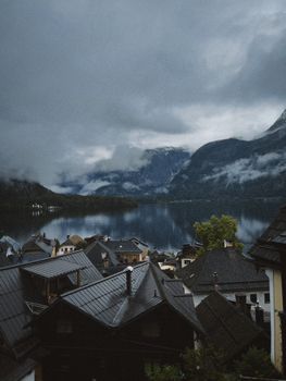 Picturesque view of a mountain village by a serene lake under a cloudy sky, perfect for travel inspiration.