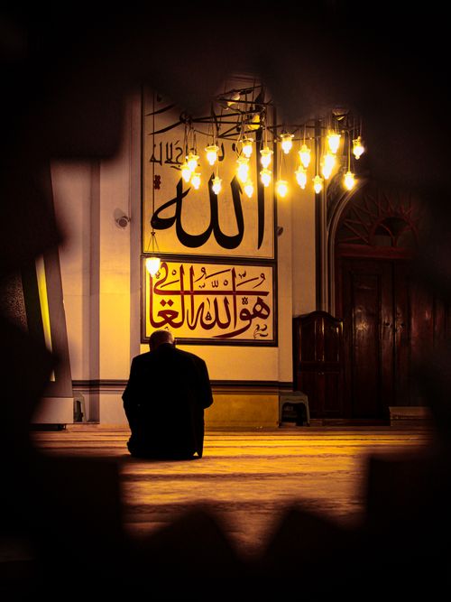 Free A peaceful scene of a man praying inside the Grand Mosque of Bursa, illuminated by warm lights. Stock Photo