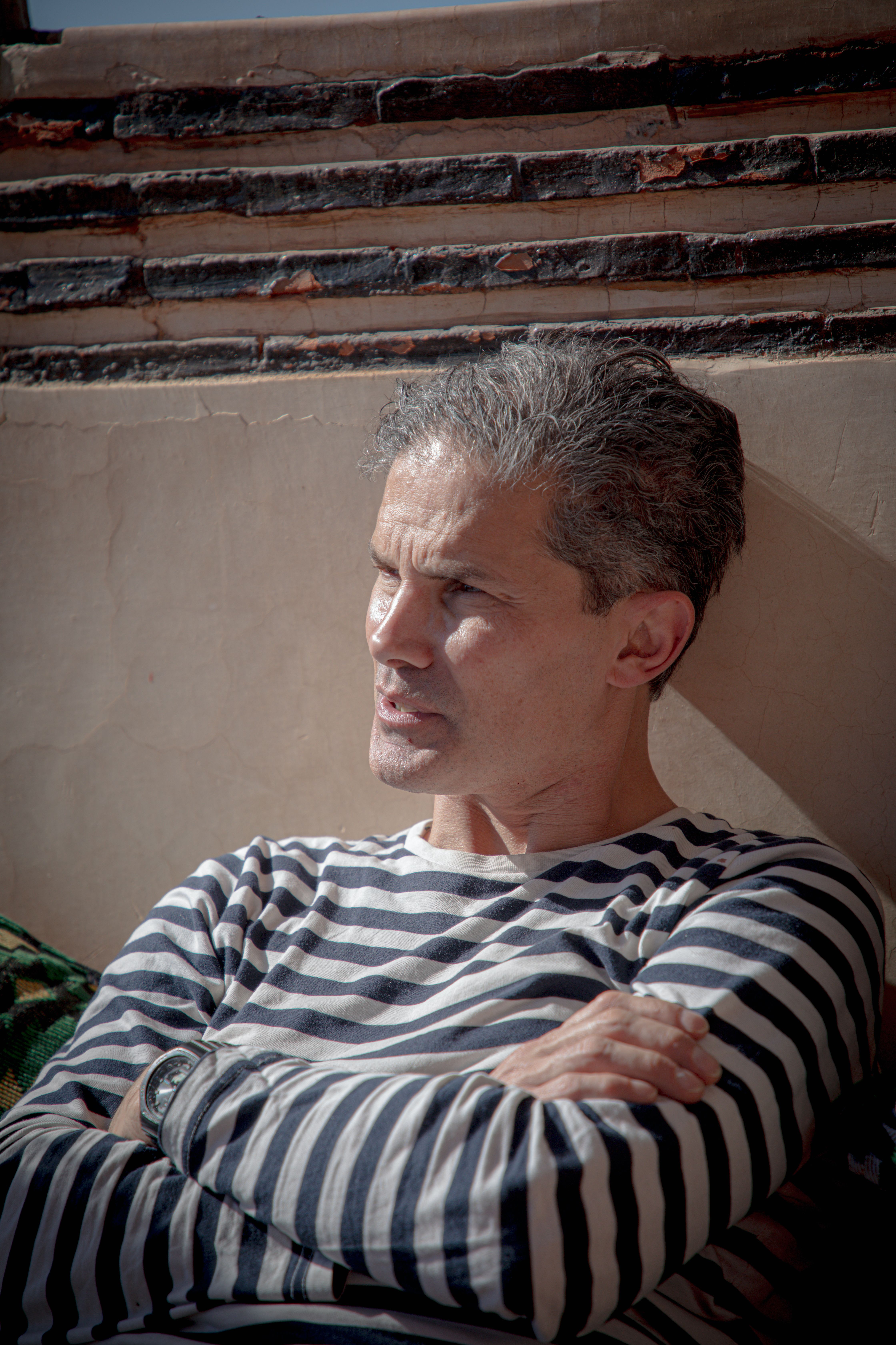 Middle-aged man relaxing in Marrakesh with natural sunlight creating a serene and thoughtful mood.
