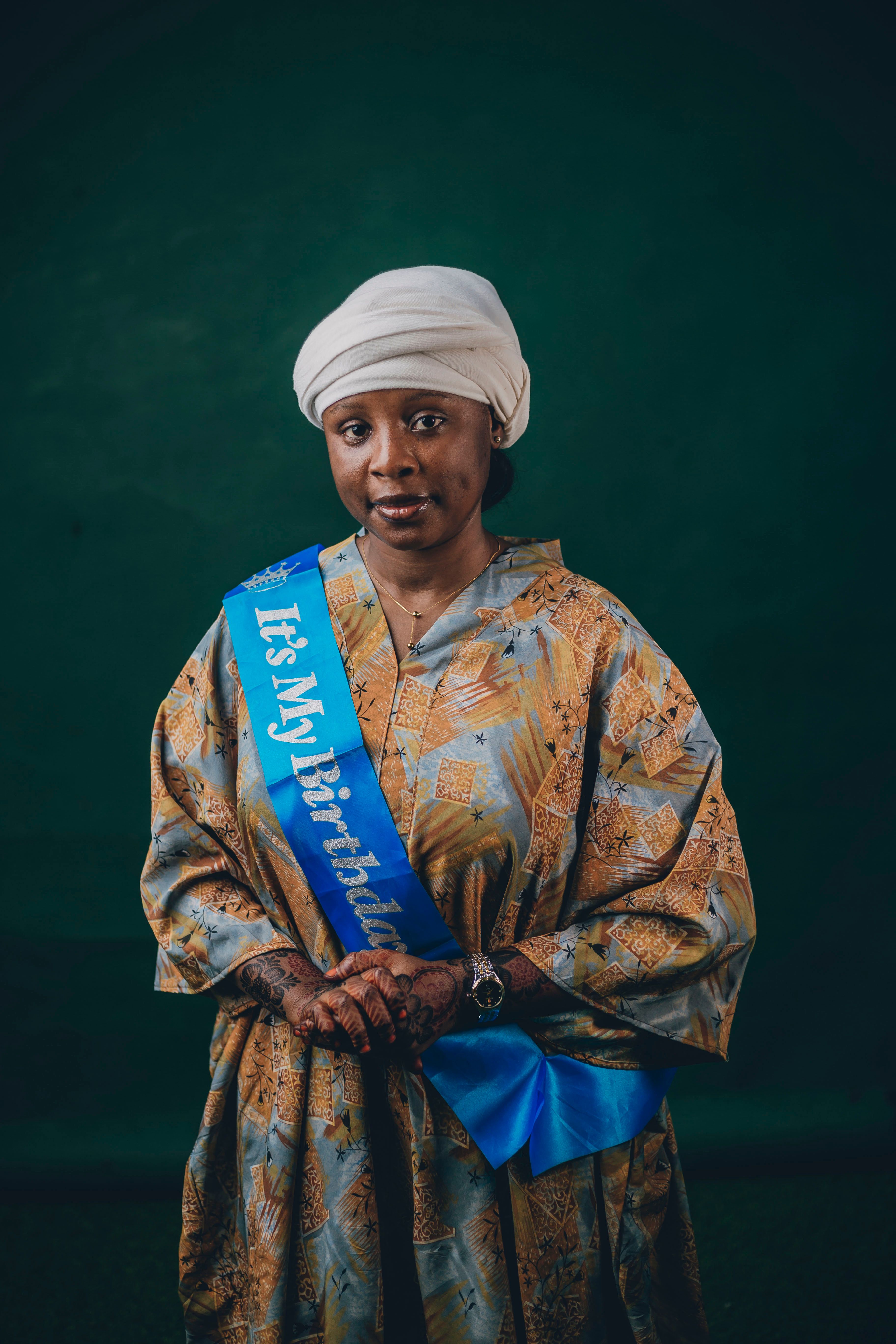 Woman in traditional clothing with birthday sash in a studio setting.