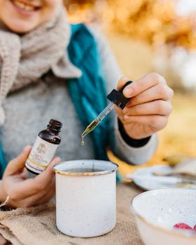 一位妇女在户外喝茶时加入草药滴剂，以促进放松和健康