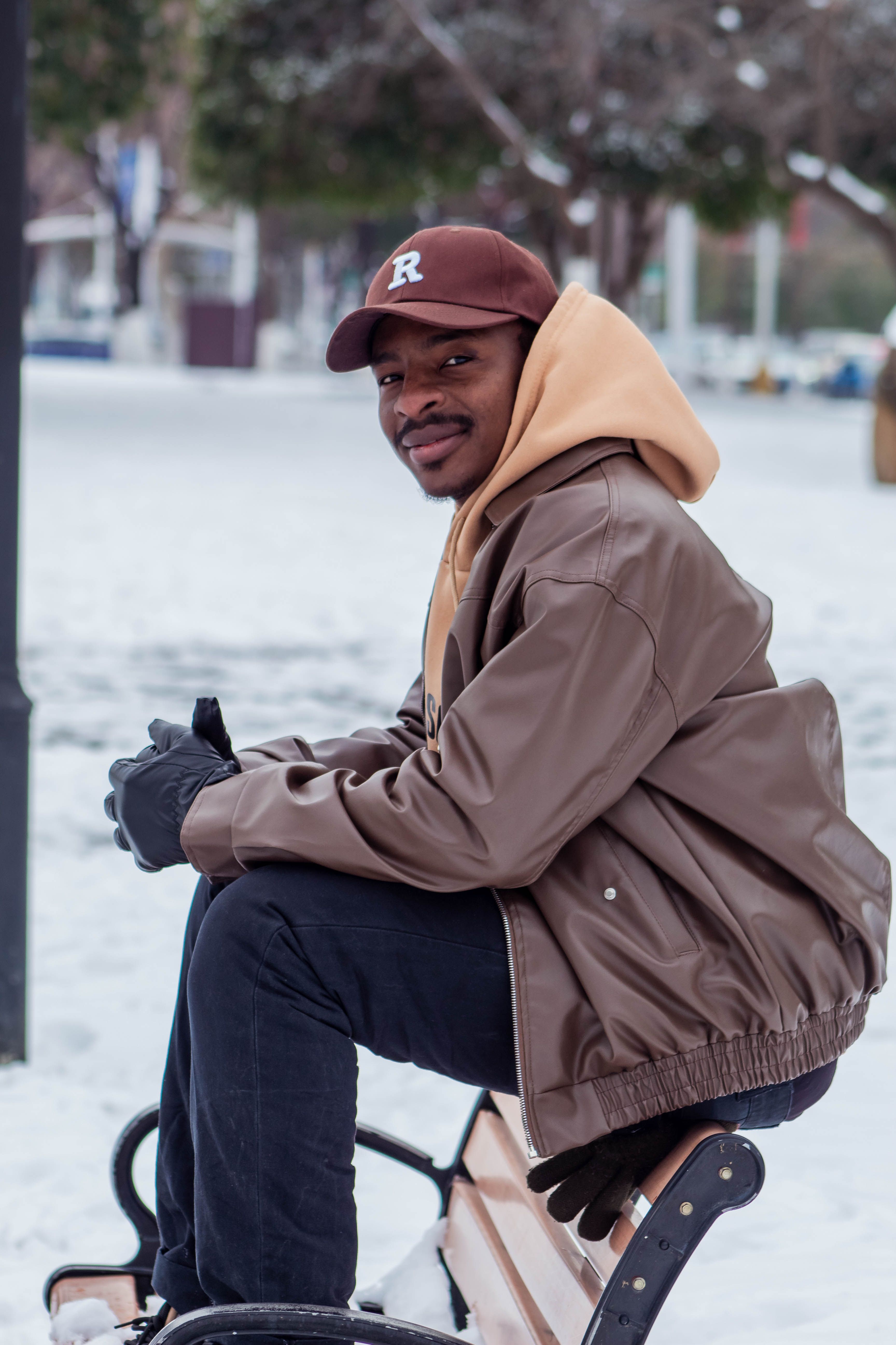 Casual winter portrait of a man seated on a park bench outdoors.