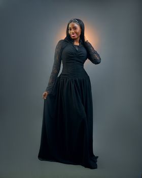 Portrait of a smiling woman in a long black dress with elegant pose.