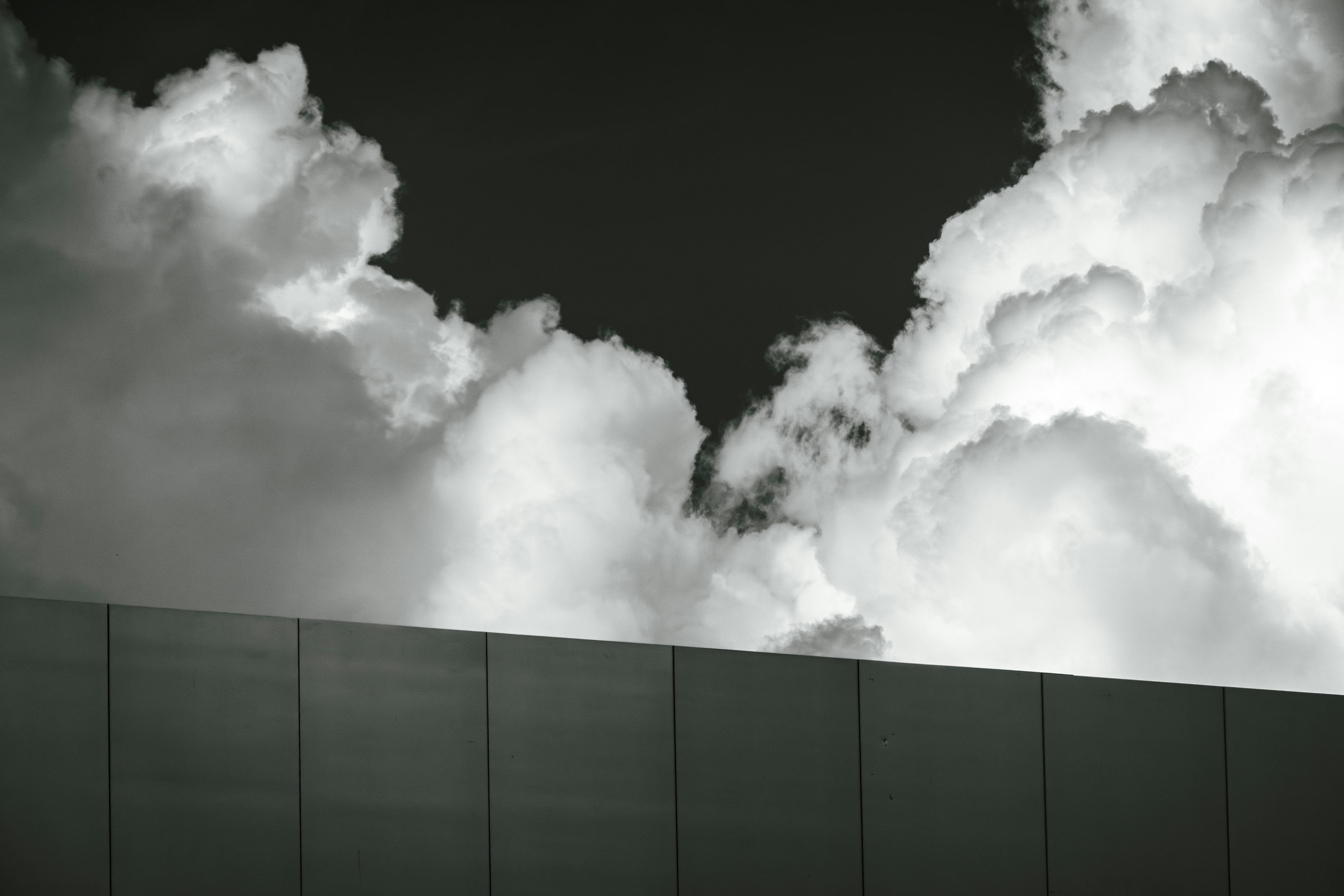 Gratis Foto in bianco e nero di nuvole imponenti sopra un edificio moderno. Foto a disposizione