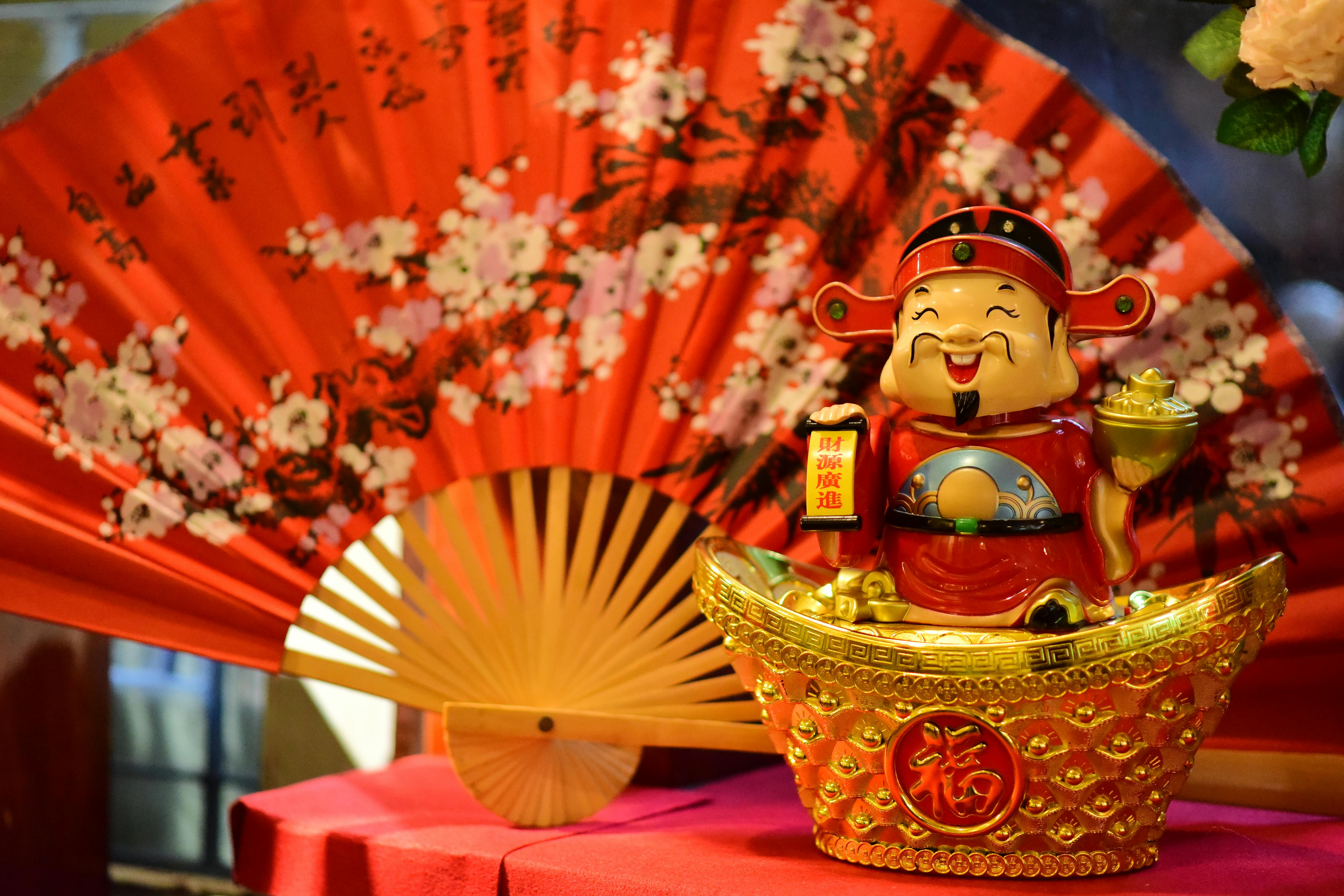 A vibrant Chinese New Year decoration featuring a lucky god and traditional fan with cherry blossoms.
