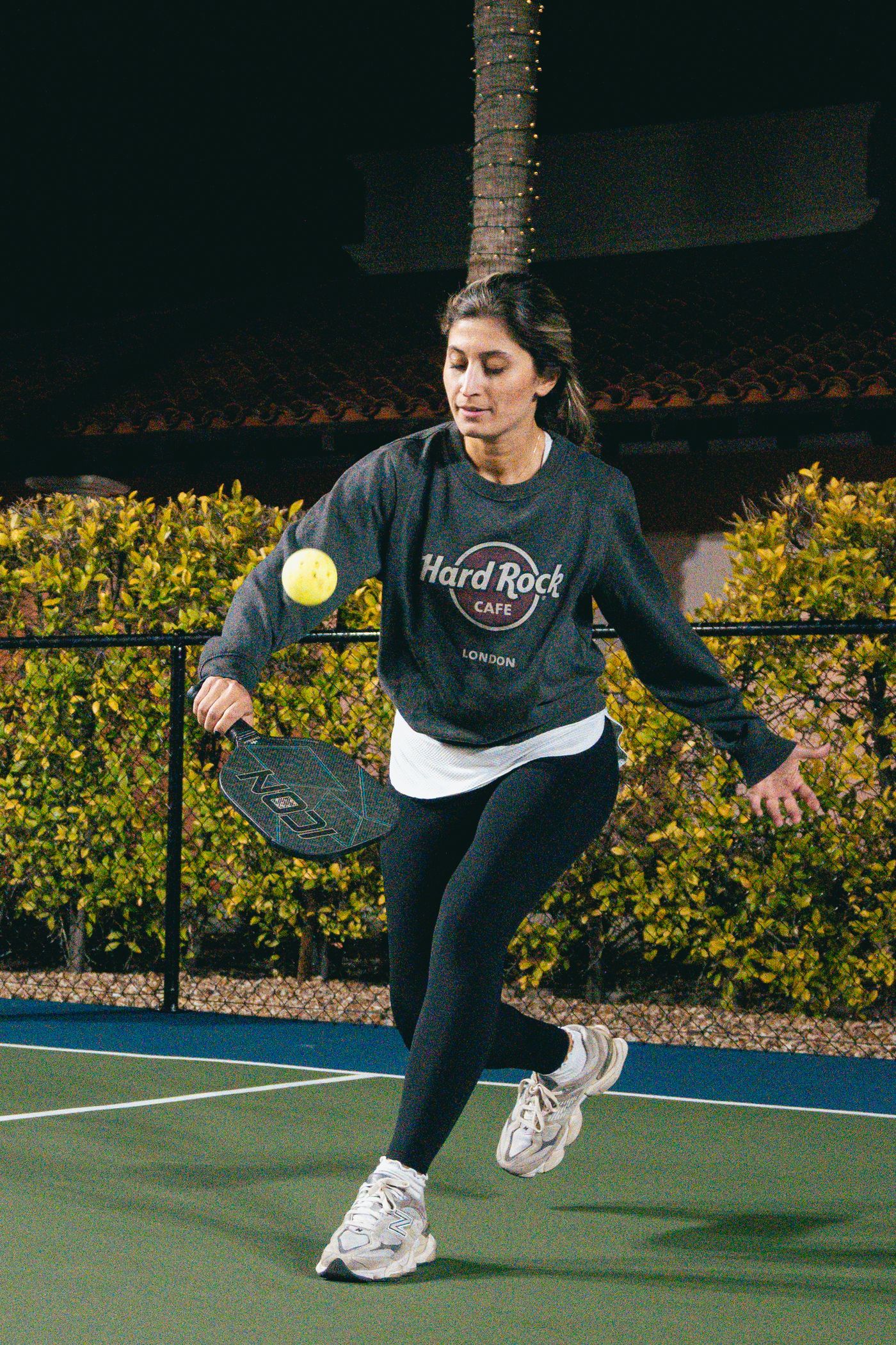 Player reaching for an energetic shot during an evening pickleball match