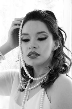 Black and white portrait of a woman wearing pearls, conveying elegance and vintage style.