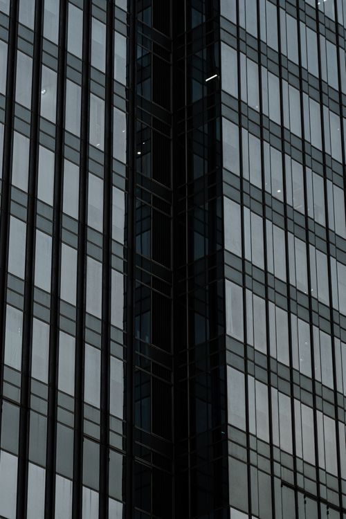 Free Close-up of a modern skyscraper facade with reflective glass windows. Stock Photo