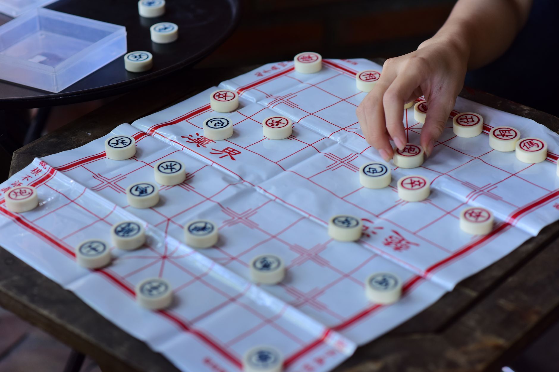 Person playing Chinese chess (Xiangqi) with traditional pieces and board.