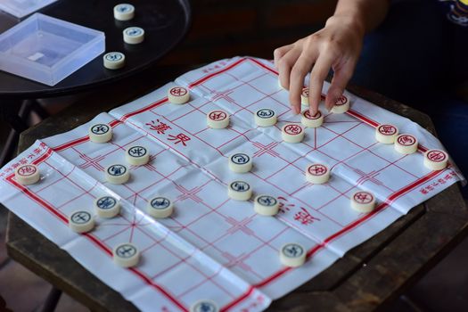 A detailed shot of a hand moving a piece on a Chinese chessboard.