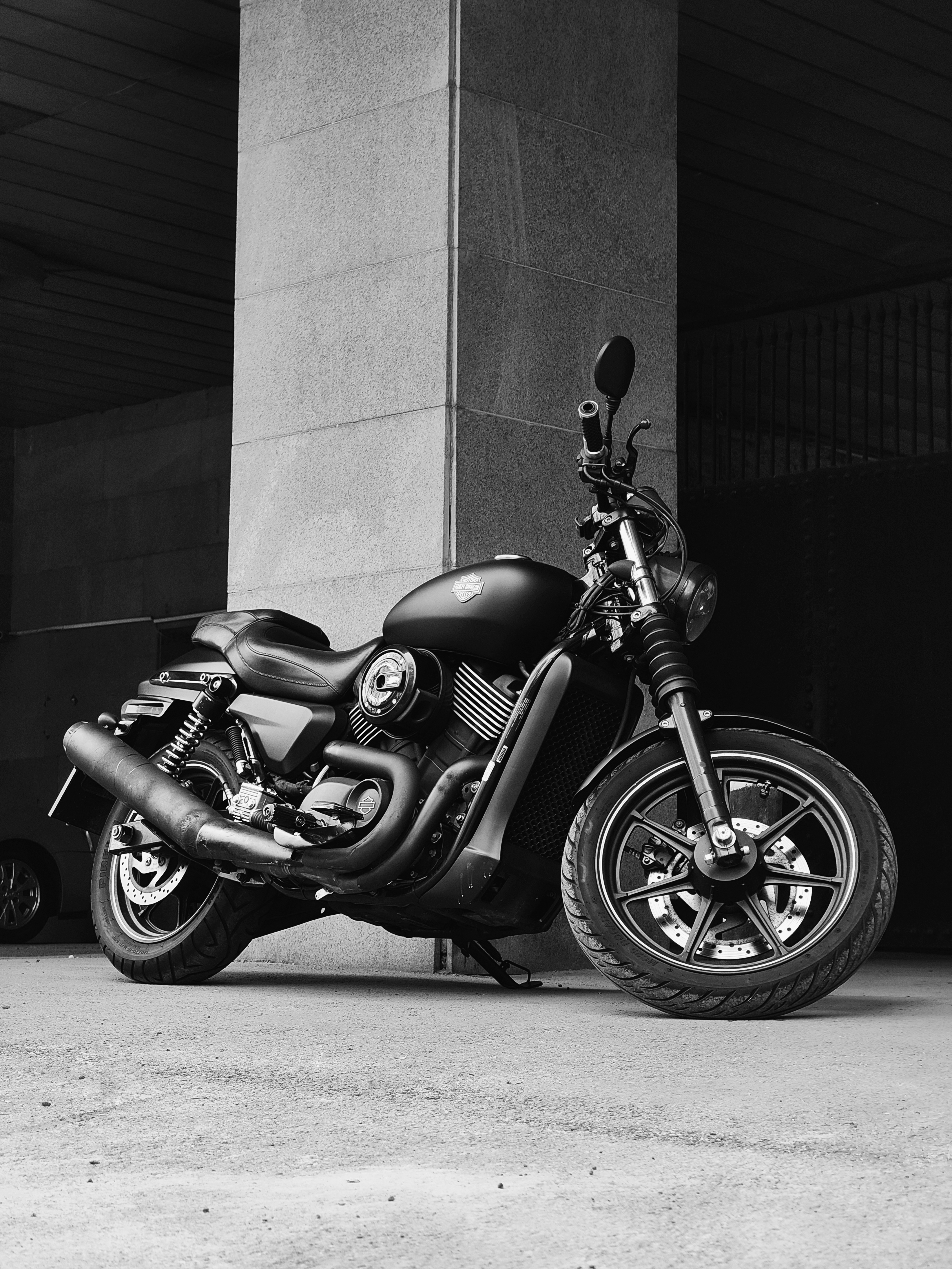 Black motorcycle parked in an urban garage, showcasing sleek design and detailed craftsmanship.