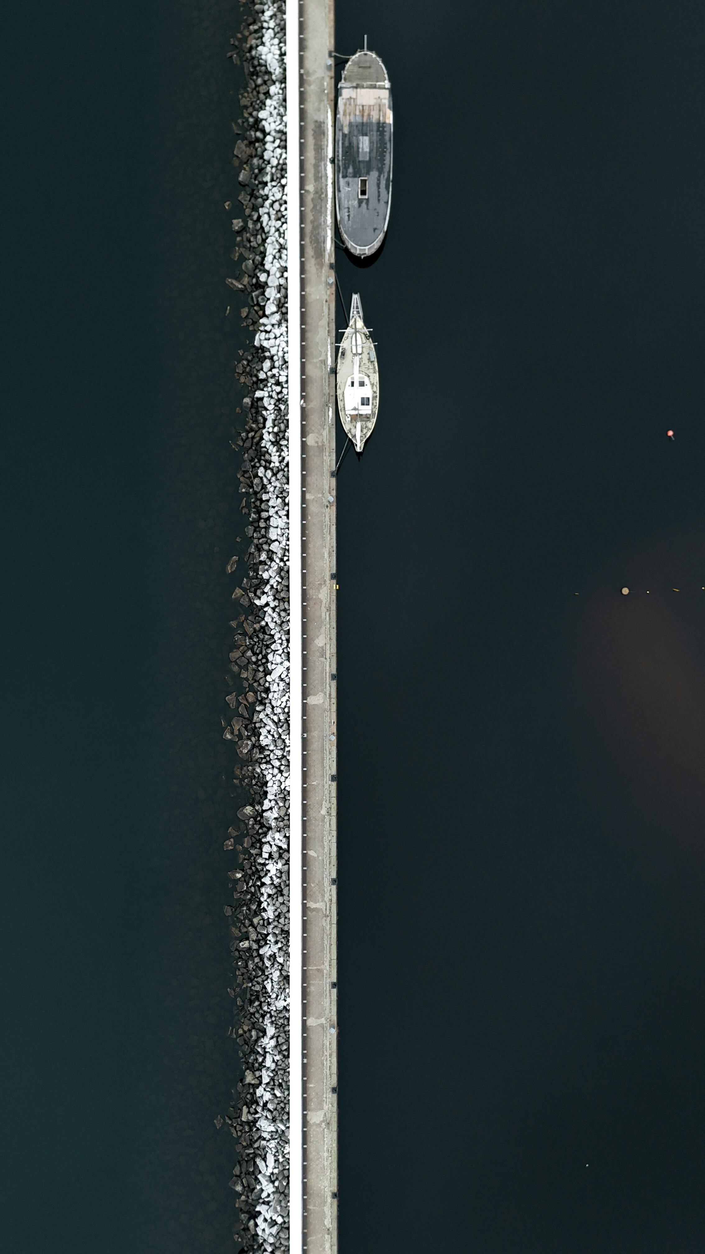 Free Aerial shot of boats docked at a pier in Jönköping, Sweden, contrasting the dark water. Stock Photo