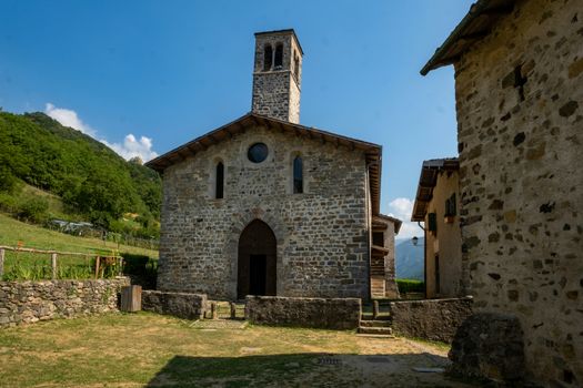 Stone church in picturesque Camerata Cornello, Lombardy, Italy, under clear skies.