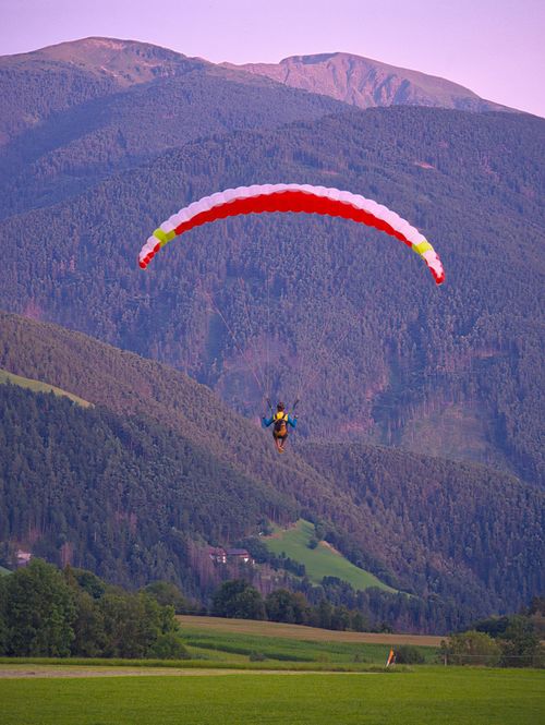 Free A paraglider soars over the picturesque mountain landscape of Trentino-Alto Adige, Italy, during sunset. Stock Photo