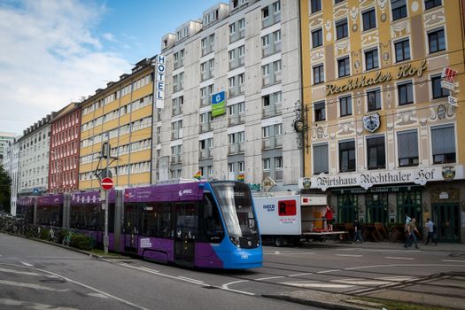 Vibrant tram traversing a lively street with Munich architecture.