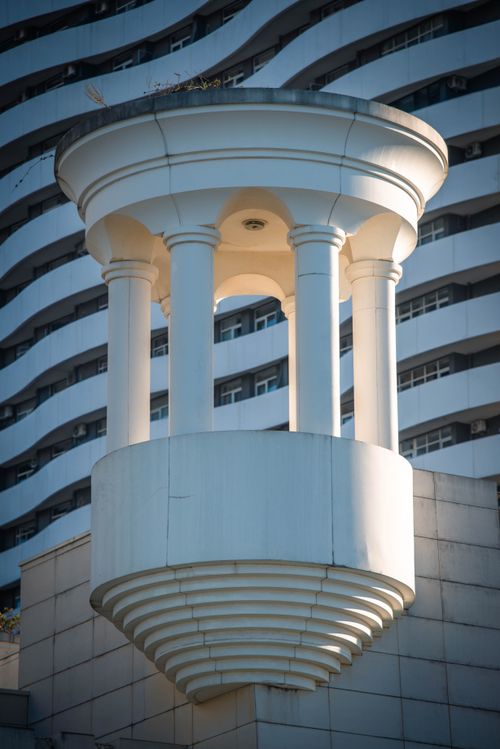 Free Modern architectural sculpture with circular elements against a wavy facade. Stock Photo