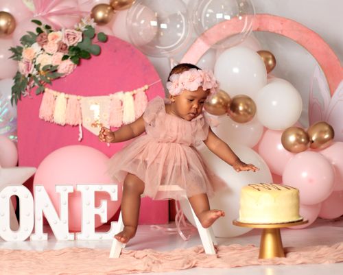 Free Adorable baby girl celebrates her first birthday with cake and balloons. Stock Photo
