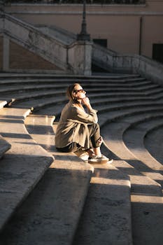 A woman enjoys sunlight on stone steps in Rome, capturing a serene moment of contemplation.